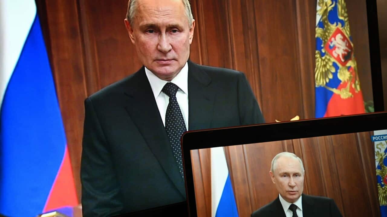 Russian President Vladimir Putin is seen on monitors as he addresses the nation