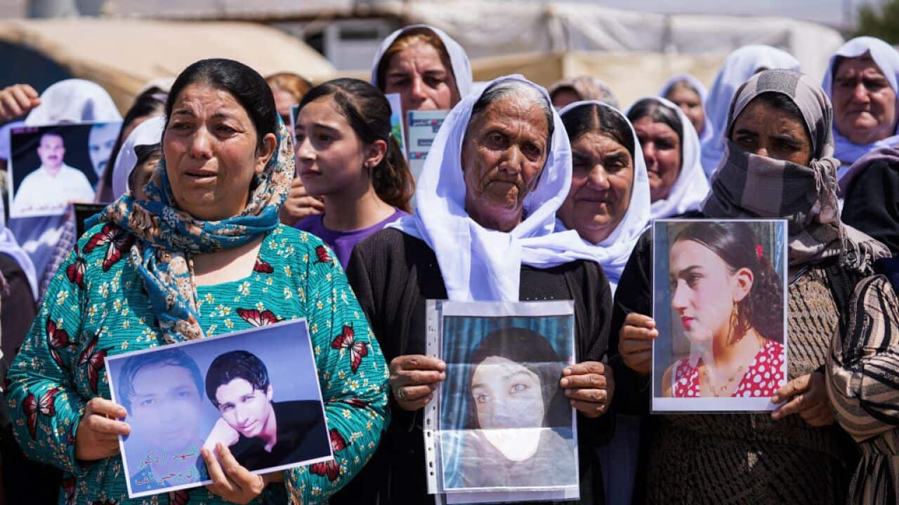 Women cry as they hold pictures of family members.