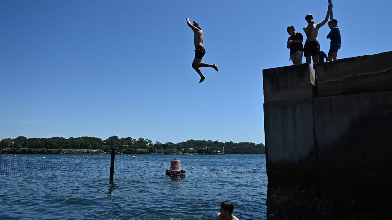 A man jumps off a raised platform into the ocean