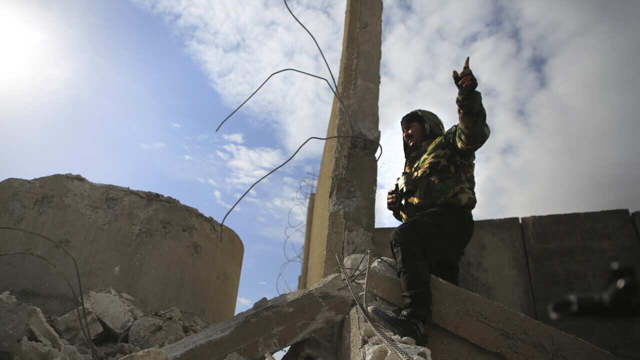 A Kurdish-led Syrian Democratic Forces fighter, stands at a damgaed part of the defense wall of Gweiran Prison, in Hassakeh, northeast Syria.
