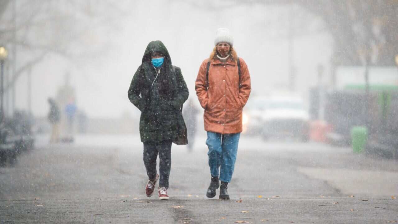 People walk in Central Park during the first snow of the season in New York City.