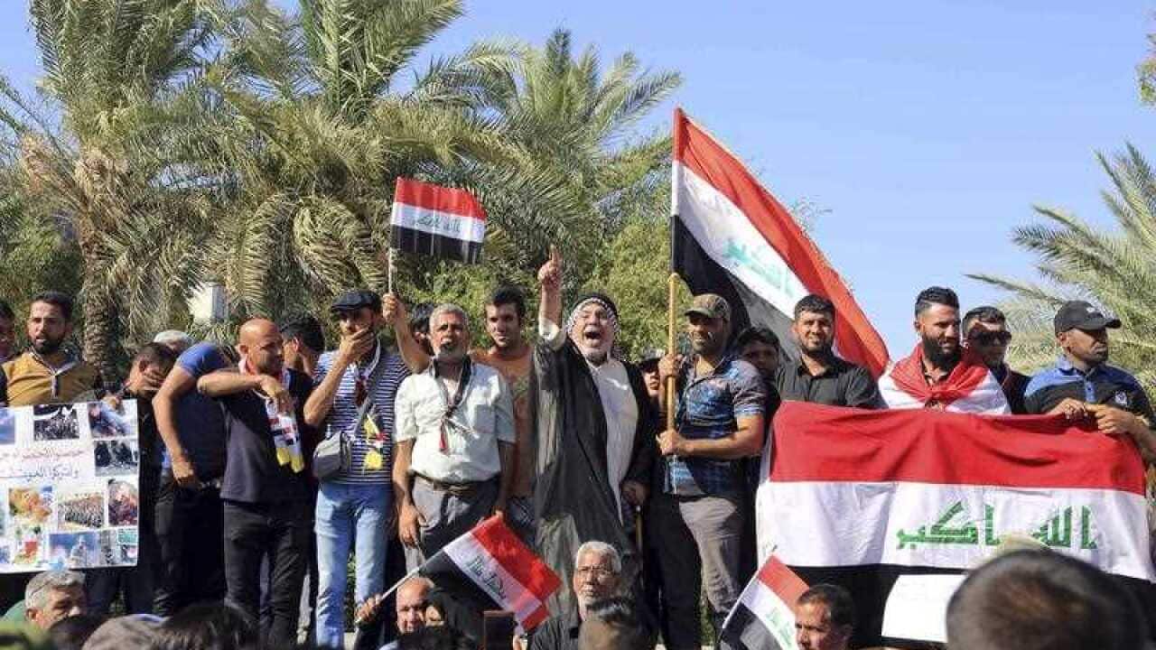 Protesters chant anti-government slogans as Iraqi security forces stand guard outside Baghdad's highly fortified Green Zone