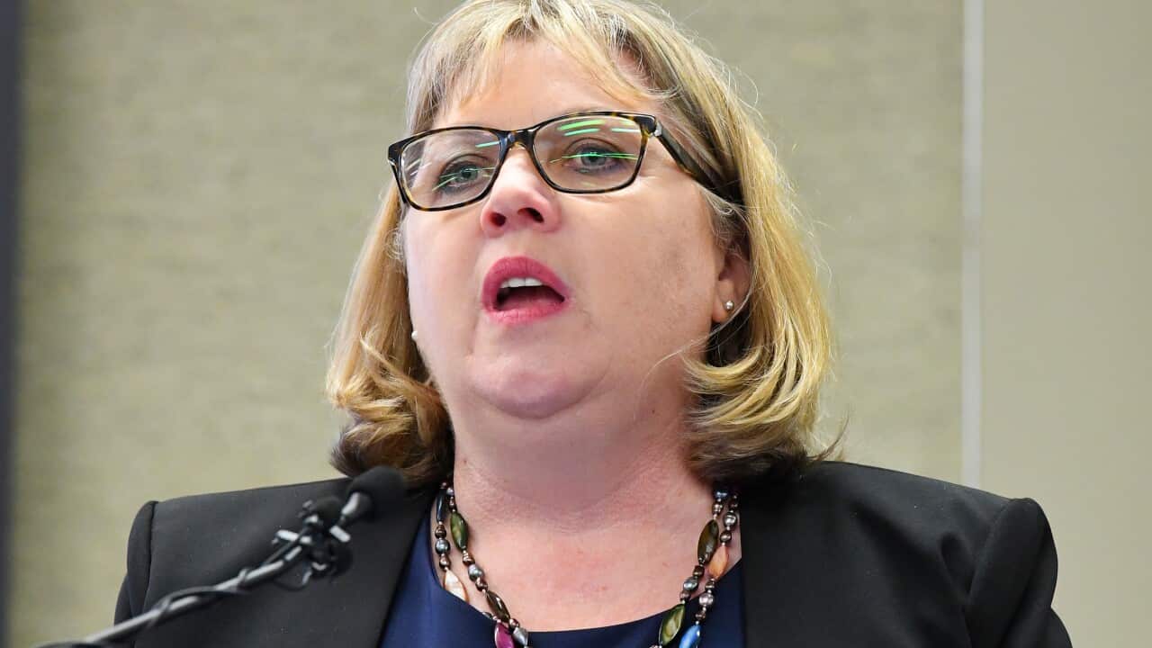 A woman standing at a lectern speaking into a microphone.