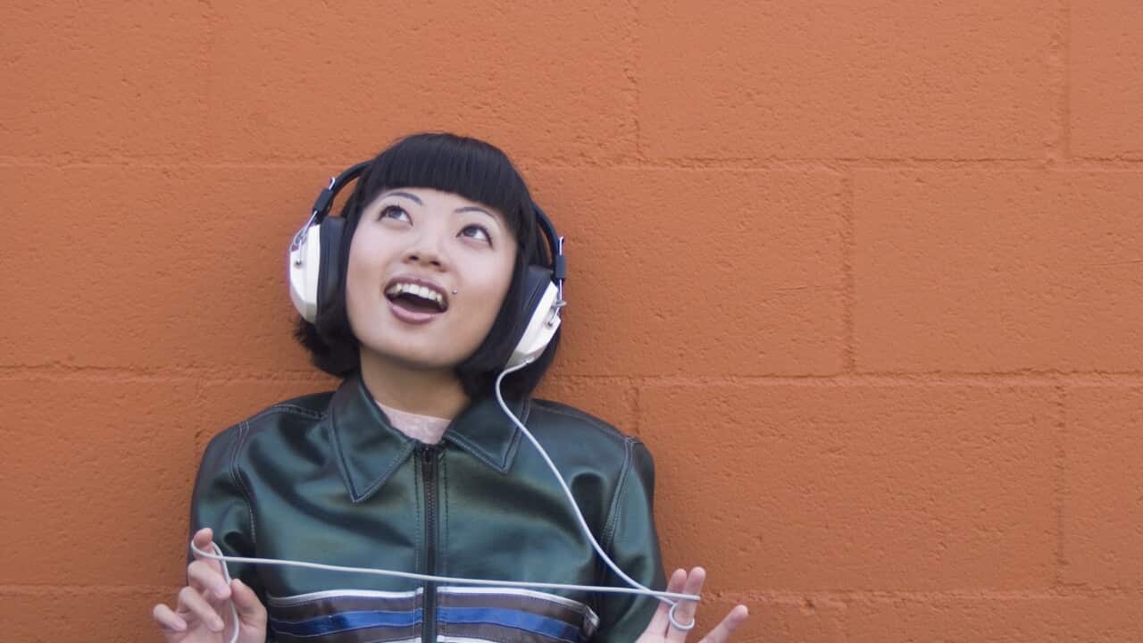 Young Asian woman listening to headphones outdoors