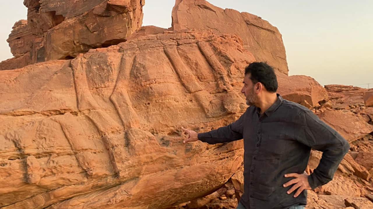 قصي التركي أمام منحوتة قديمة.png