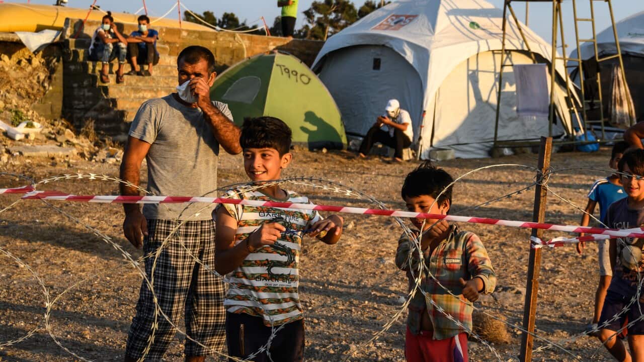 Adults and minors refugees and migrants stand behind razor wire at the Kara Tepe camp on Lesbos island, Greece, 19 September 2020