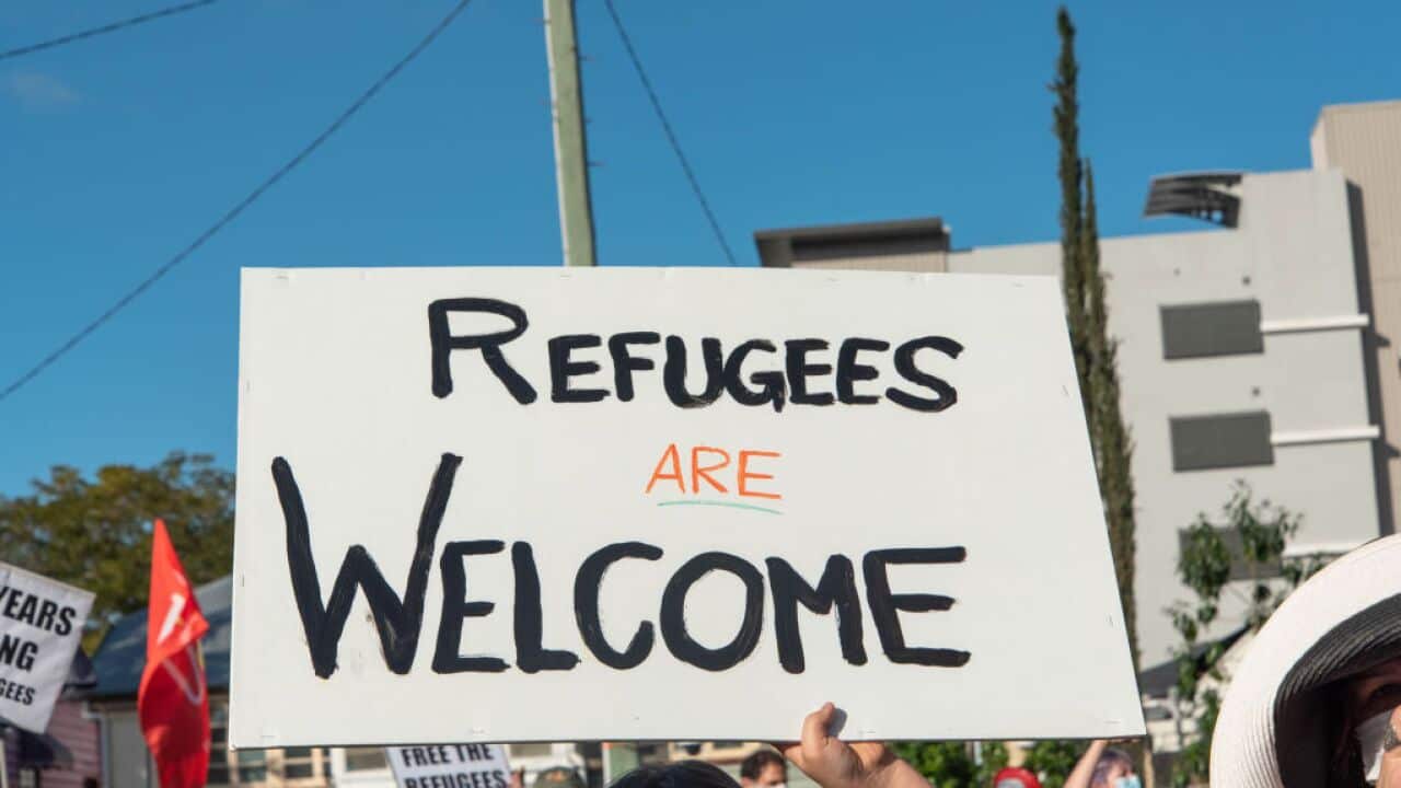 A protester holds a sign saying 'Refugees are welcome'