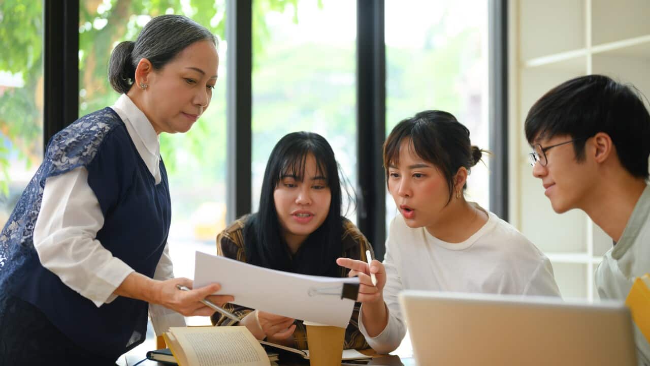 University students working on their assignment with help from teacher