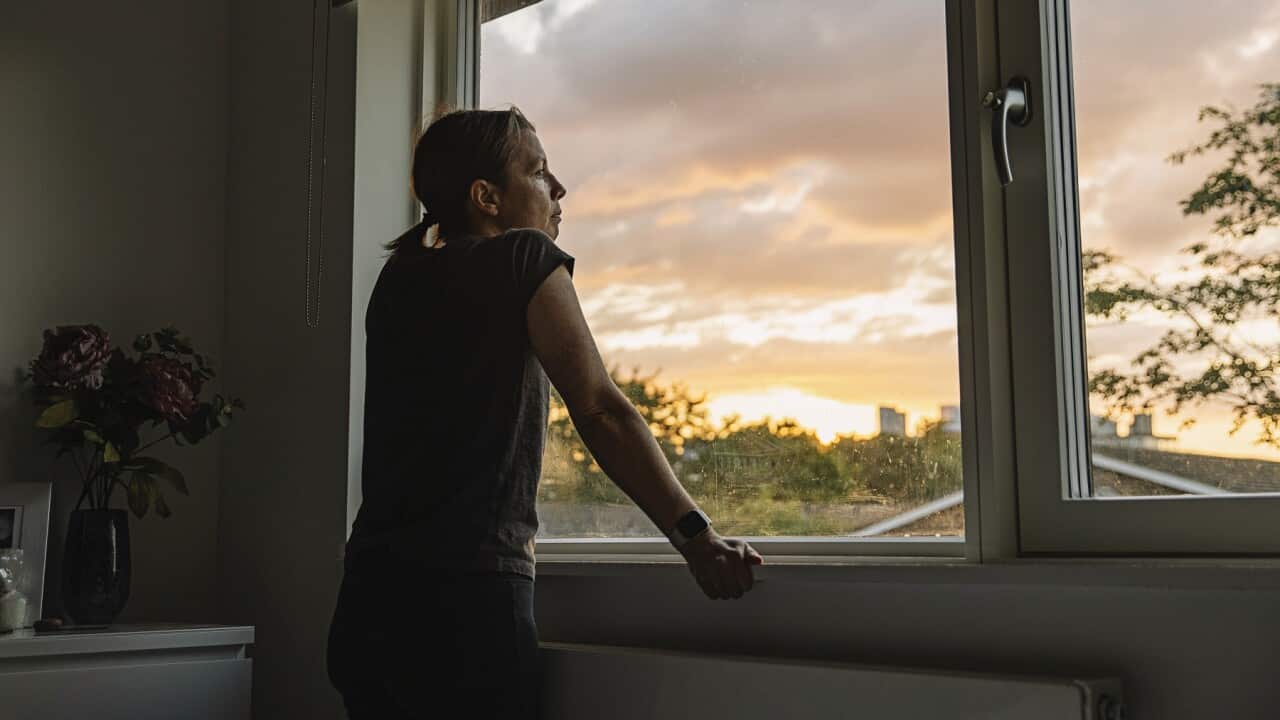 Woman looking out of window at sunset