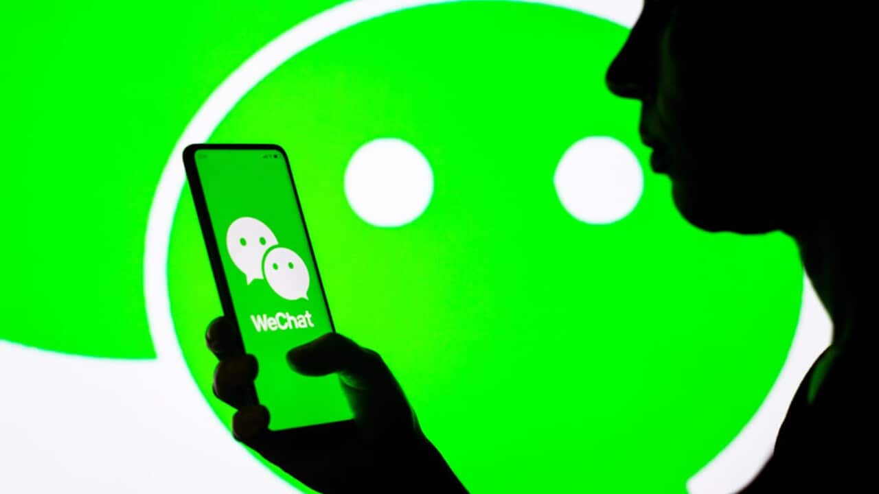 A woman holds a photo with the WeChat logo.