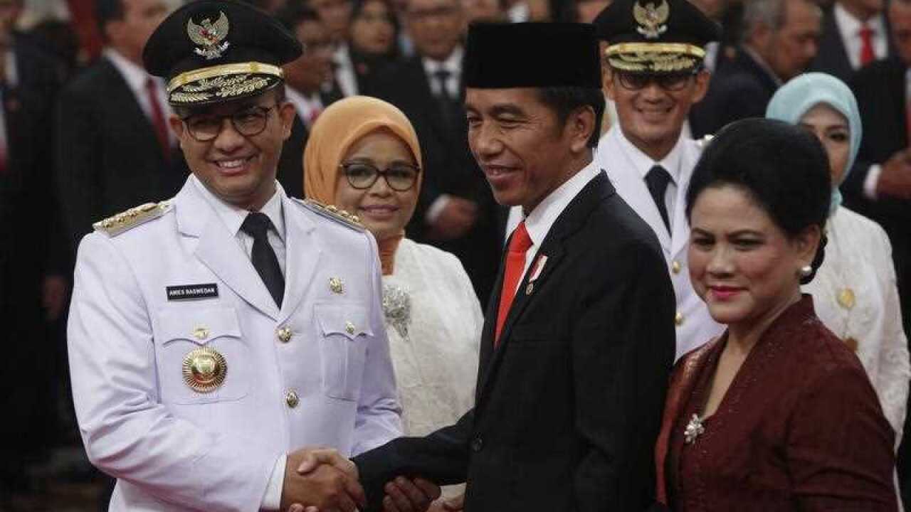 Newly elected Jakarta Governor Anies Baswedan (L) is greeted by Indonesian President Joko Widodo (C) and wife Iriana Widodo (R)