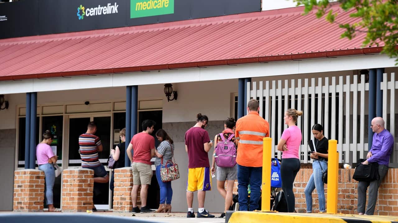 People are seen in a long queue outside a Centrelink office in Brisbane