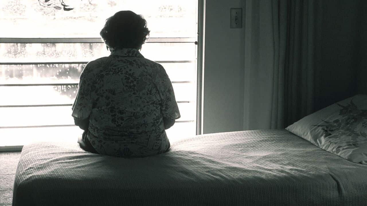Elderly Female Silhouette, Sitting On Her Bed Looking Out Window.