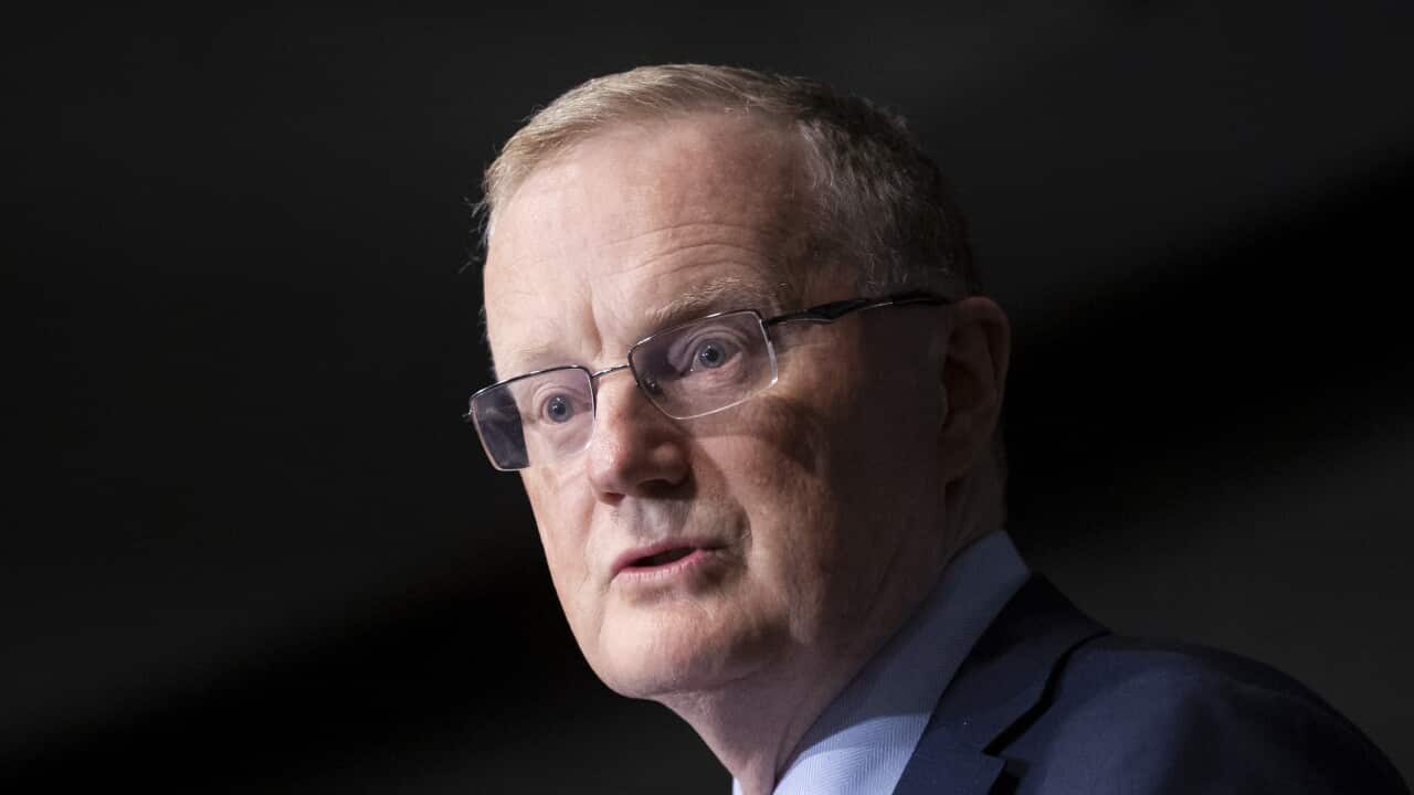 A man wearing glasses, a light blue shirt, navy blazer, and striped tie