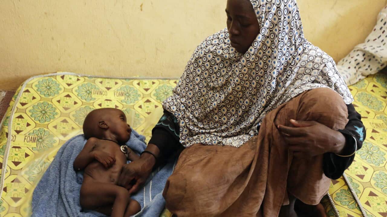 A woman rescued from Boko Haram looks at her malnourished child