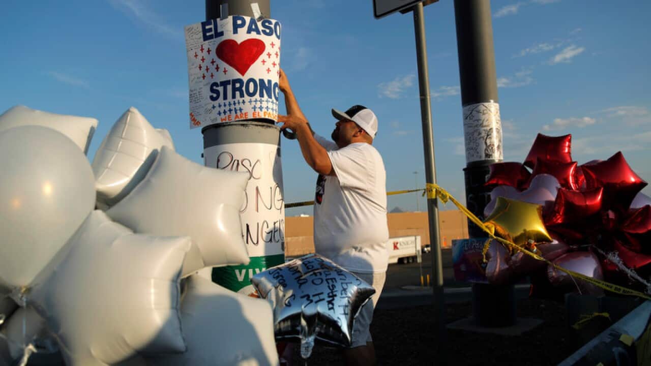A man hangs up an 'El Paso Strong' sign at the scene of a mass shooting in El Paso
