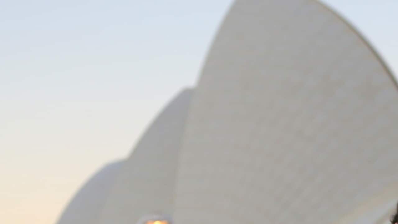 People walk in front of the Sydney Opera House during windy weather in Sydney, Saturday, July 13, 2019. (AAP Image/Steven Saphore) NO ARCHIVING