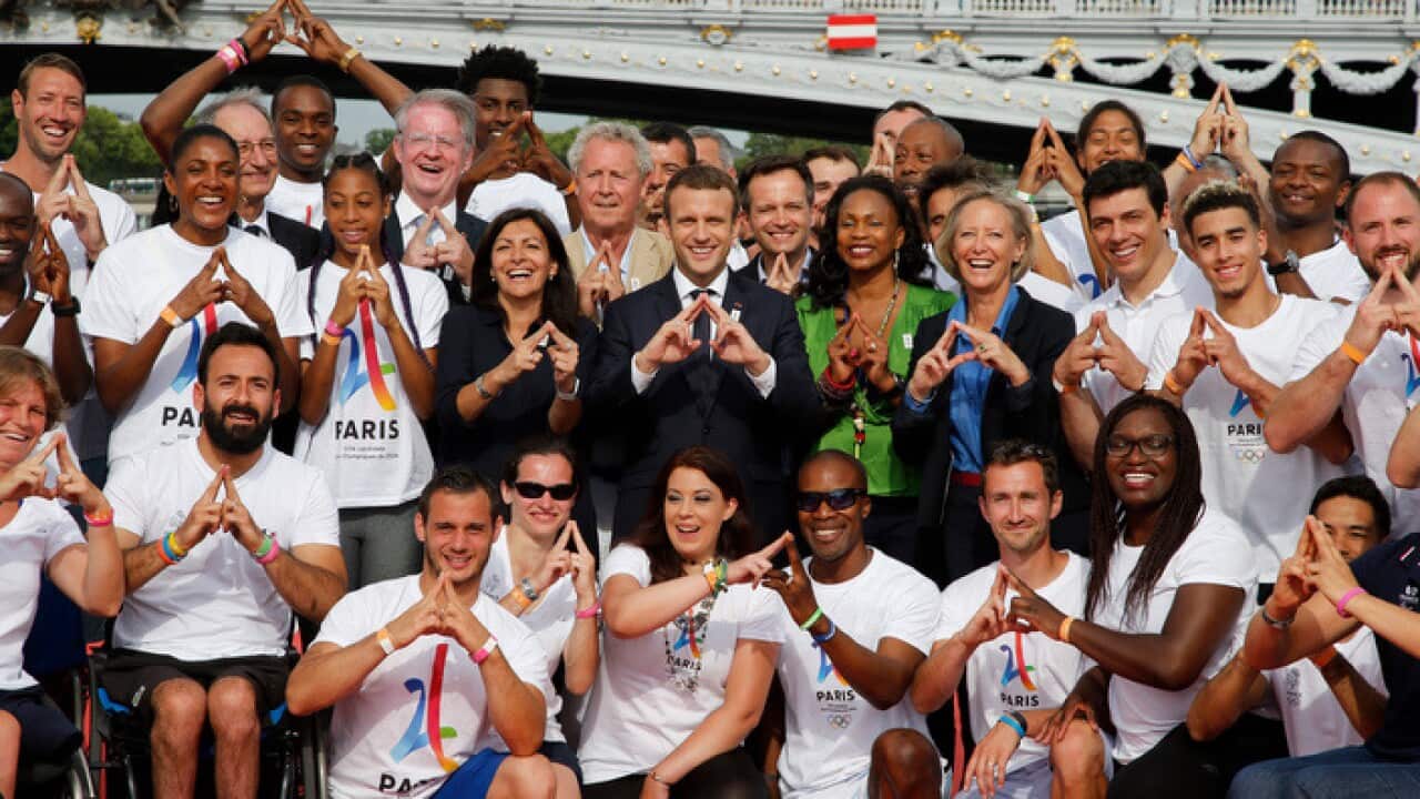 French President Emmanuel Macron, center, stands with city mayor Anne Hidalgo, center left, and Sports Minister Laura Flessel