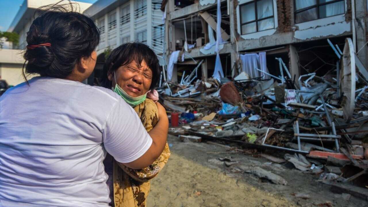 A woman mourns as rescuers search for earthquake victim from inside a damaged hotel building in Palu, Central Sulawesi, Indonesia