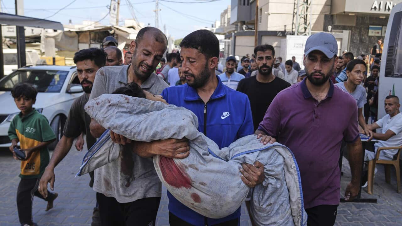 Men crying and carrying a young girl in a makeshift body bag.