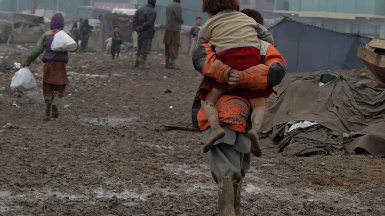 File photo from 2012 of an Afghan displaced child carrying another child on his back