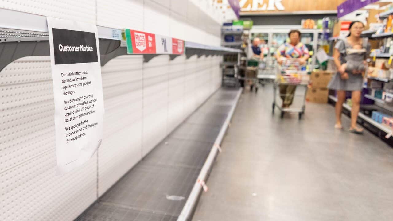 Customers looks at empty shelves at a supermarket.