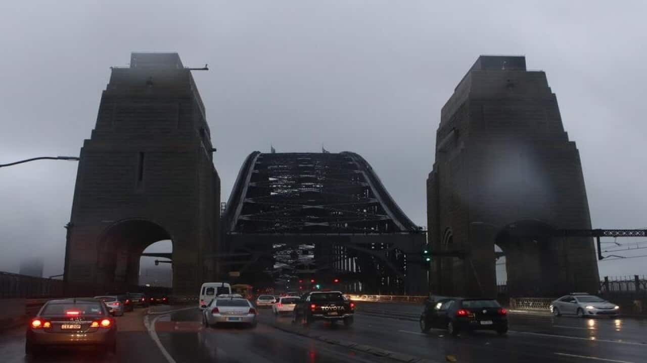 Cars cross the Harbour Bridge during a grey summer evening in Sydney.