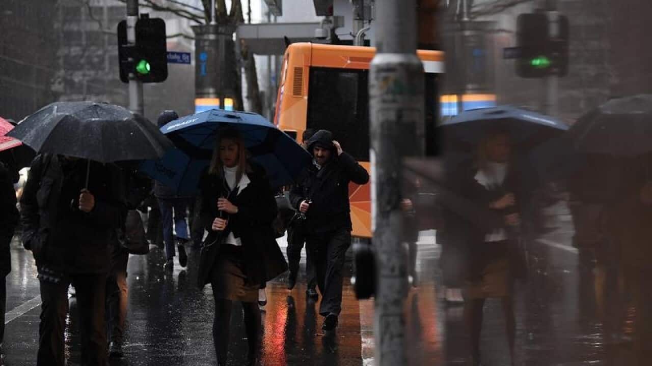 Pedestrians crossing an intersection during rain in Melbourne.