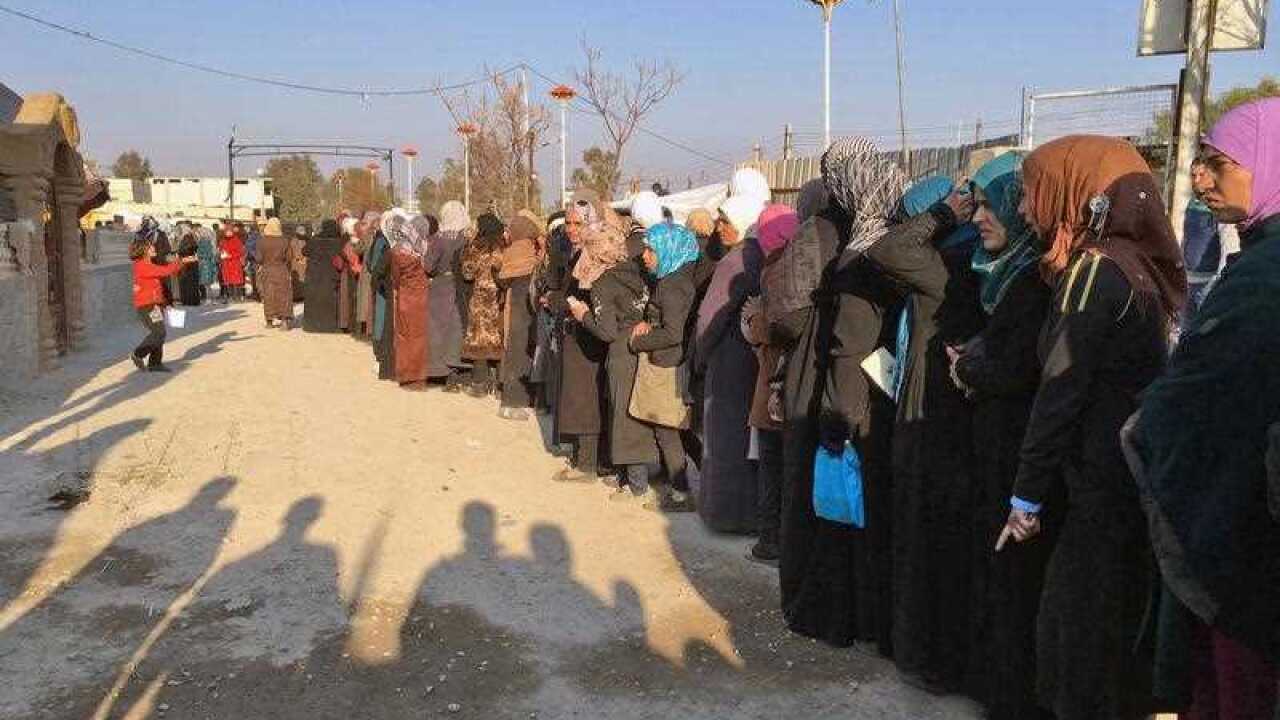 Lines of people weaving through a street in the besieged town of Moadamiyeh, Syria during a food aid distribution that took place in a buffer zone on the edge of the besieged city.