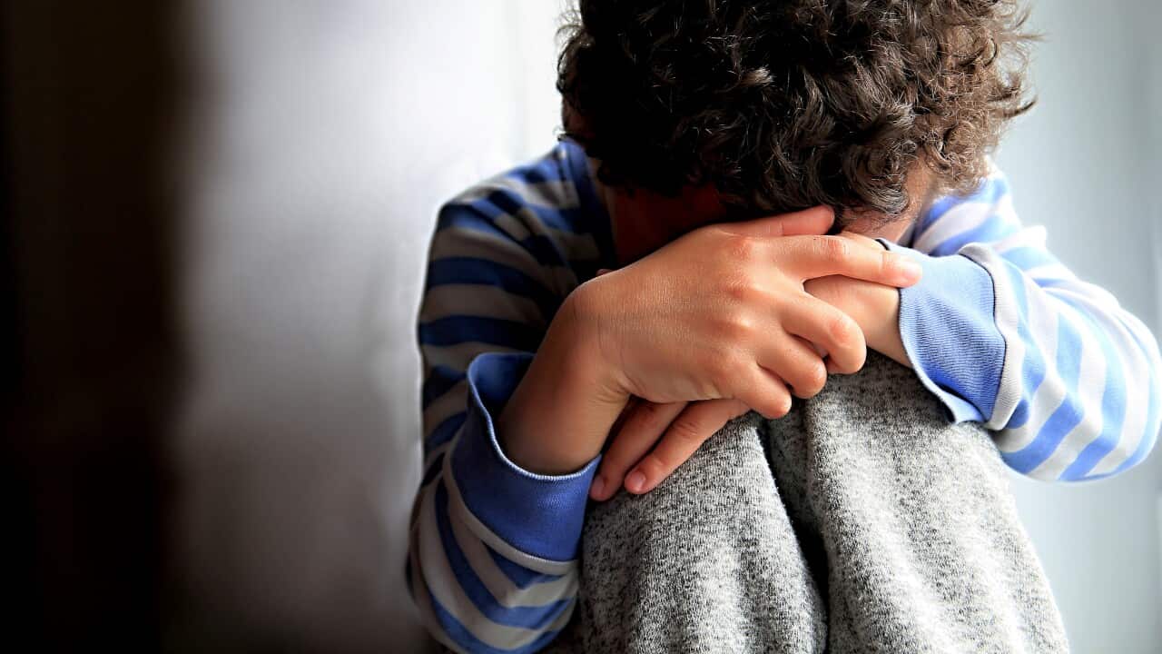 Boy Praying With Hands Over Face Against Wall At Home Stock Photo