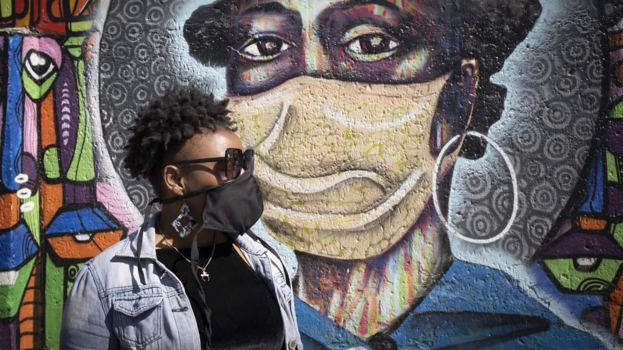 A Soweto resident in front of artwork educating residents about the dangers of COVID-19.