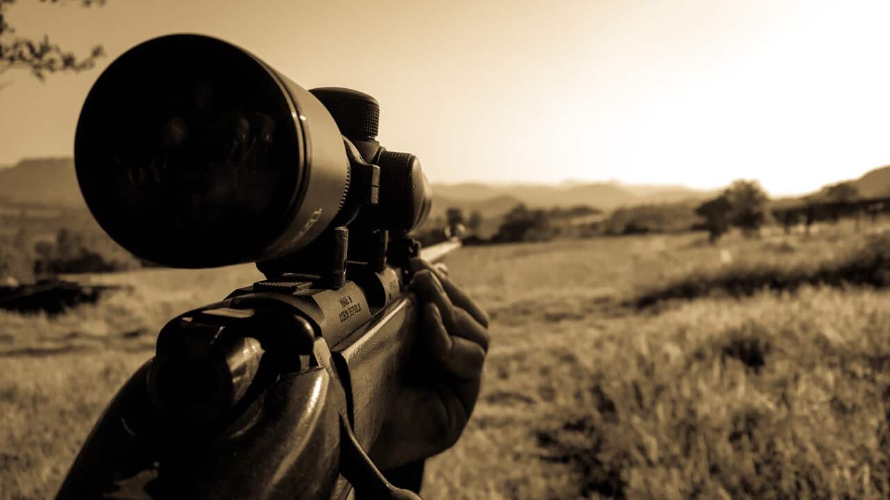 A poacher holds a gun