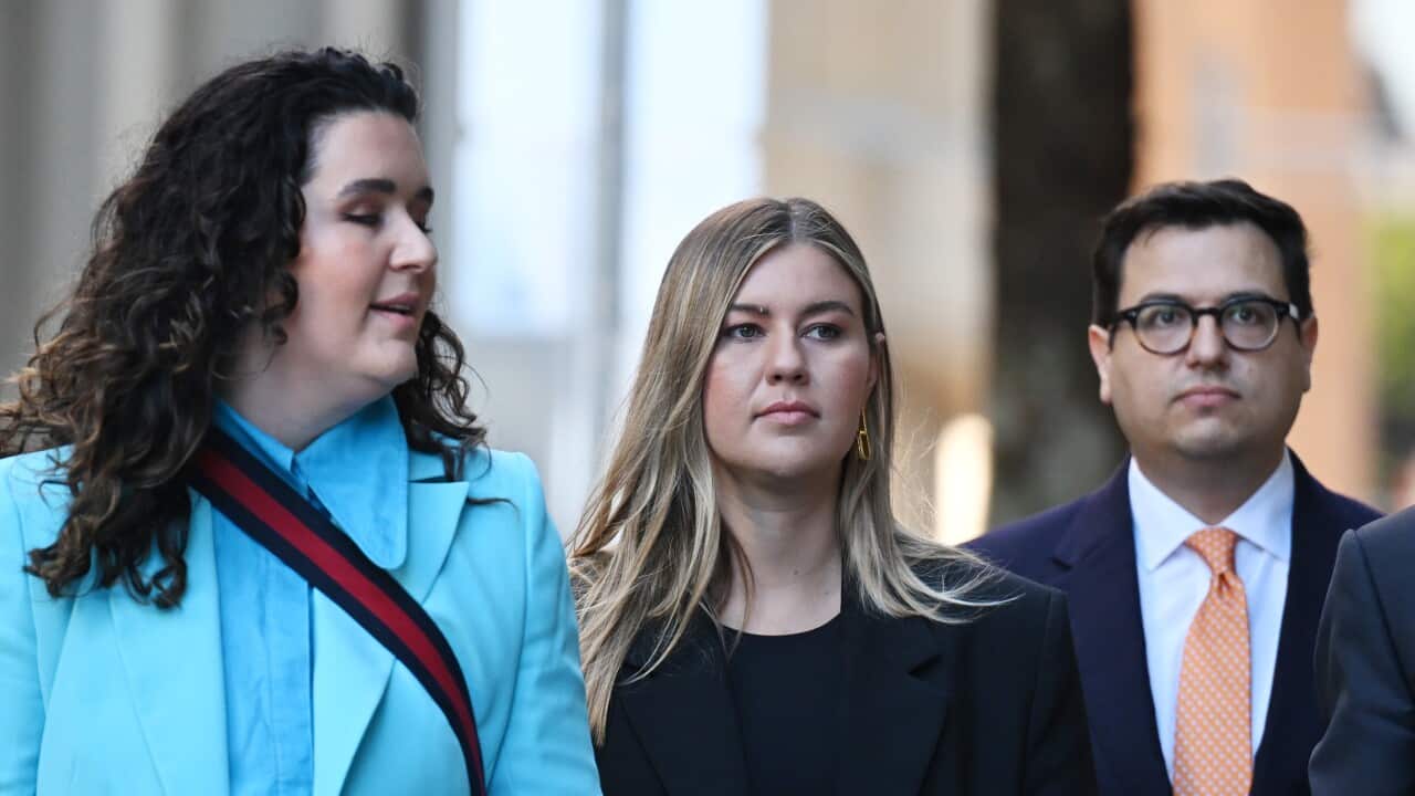 A woman in a blue suit next to a woman in a black suit and a man in a navy suit