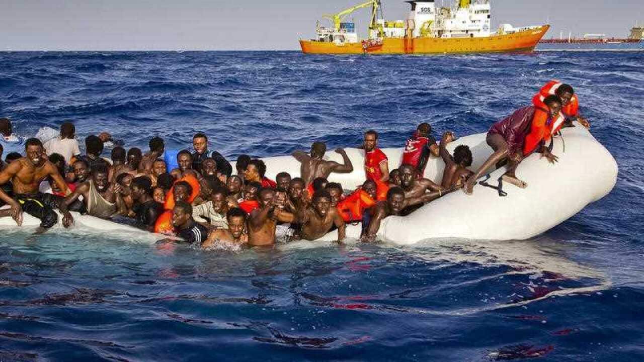 In this photo taken on Sunday, April 17, 2016 migrants ask for help from a dinghy boat as they are approached by the SOS Mediterranee's ship Aquarius