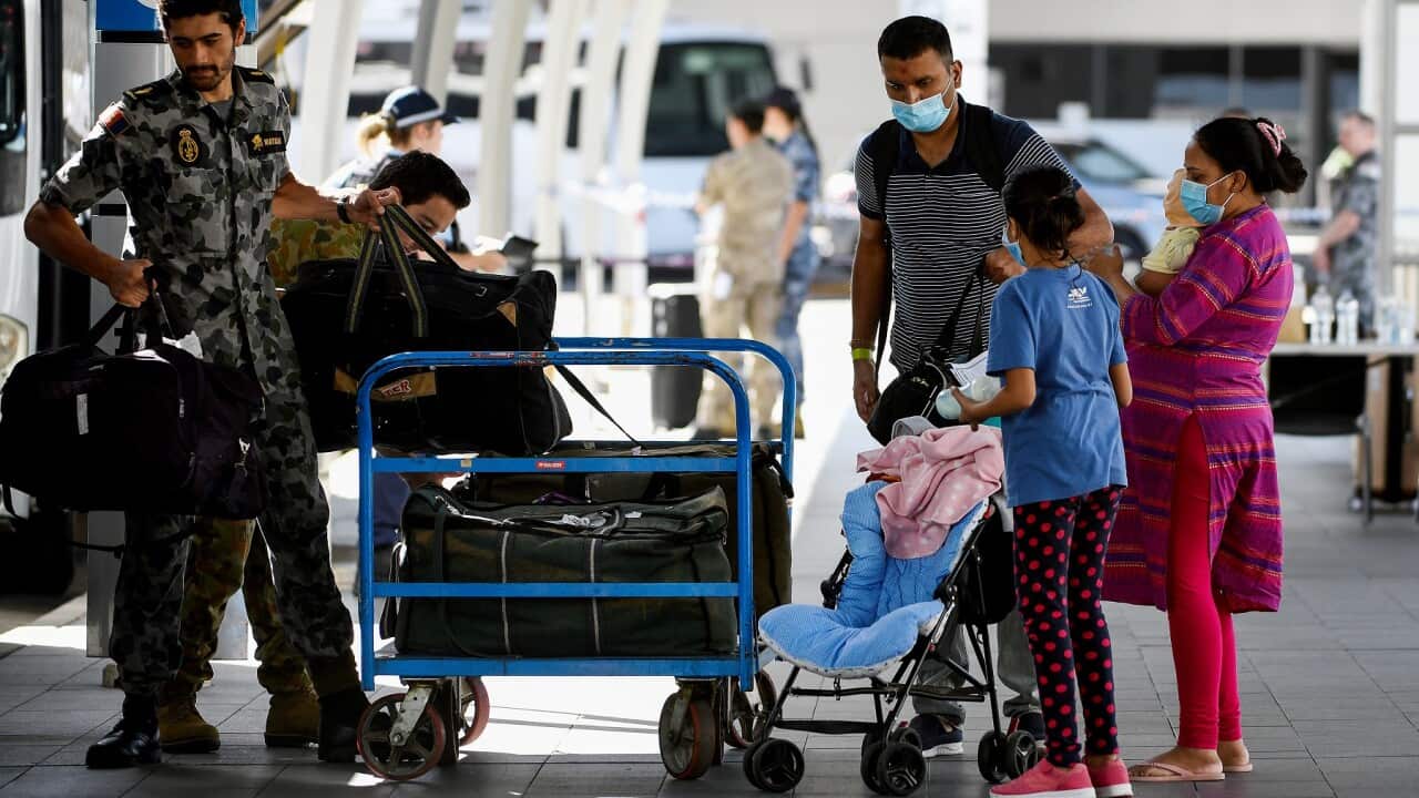 Australian residents returning from India at Sydney International Airport are helped by Royal Australian Navy officers.