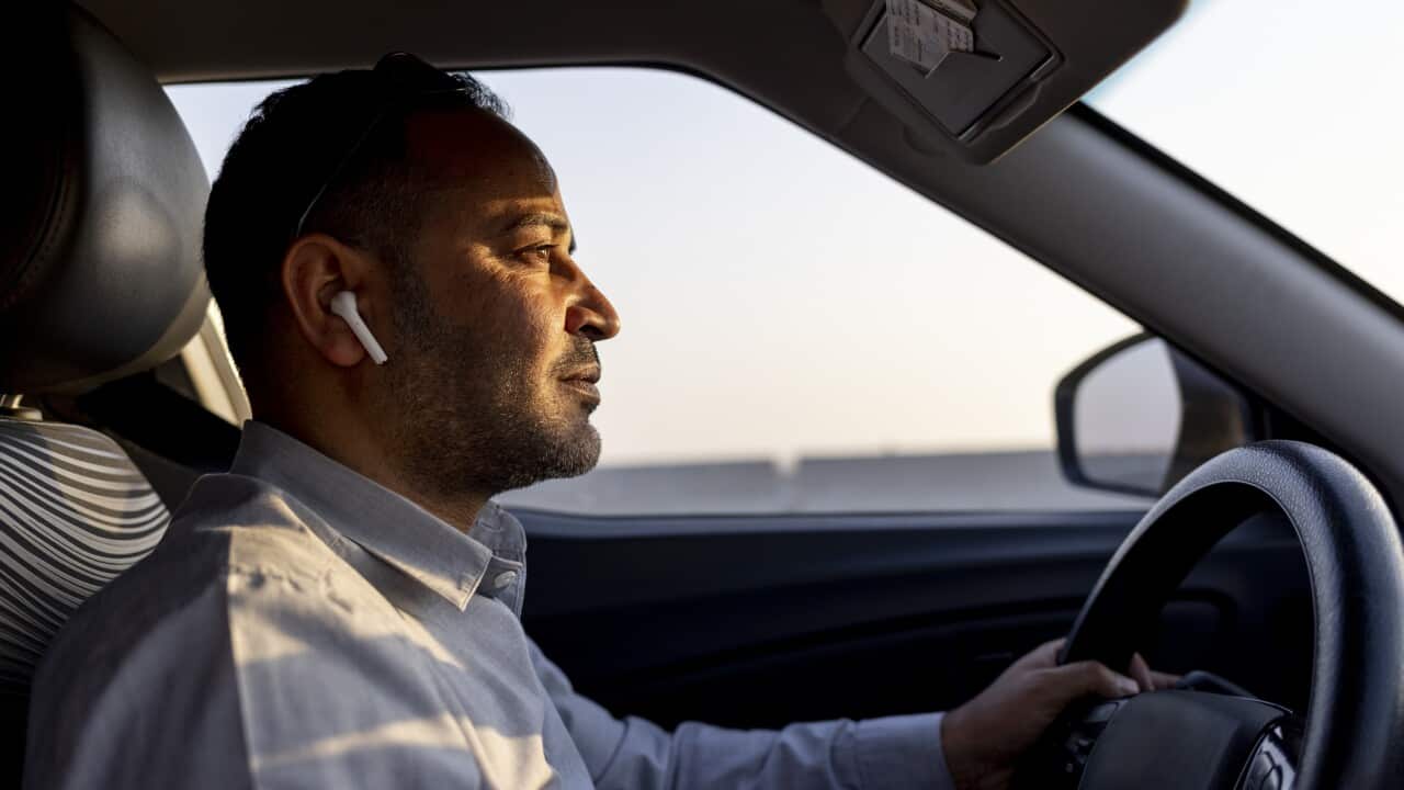 business man using ear pods while driving a car