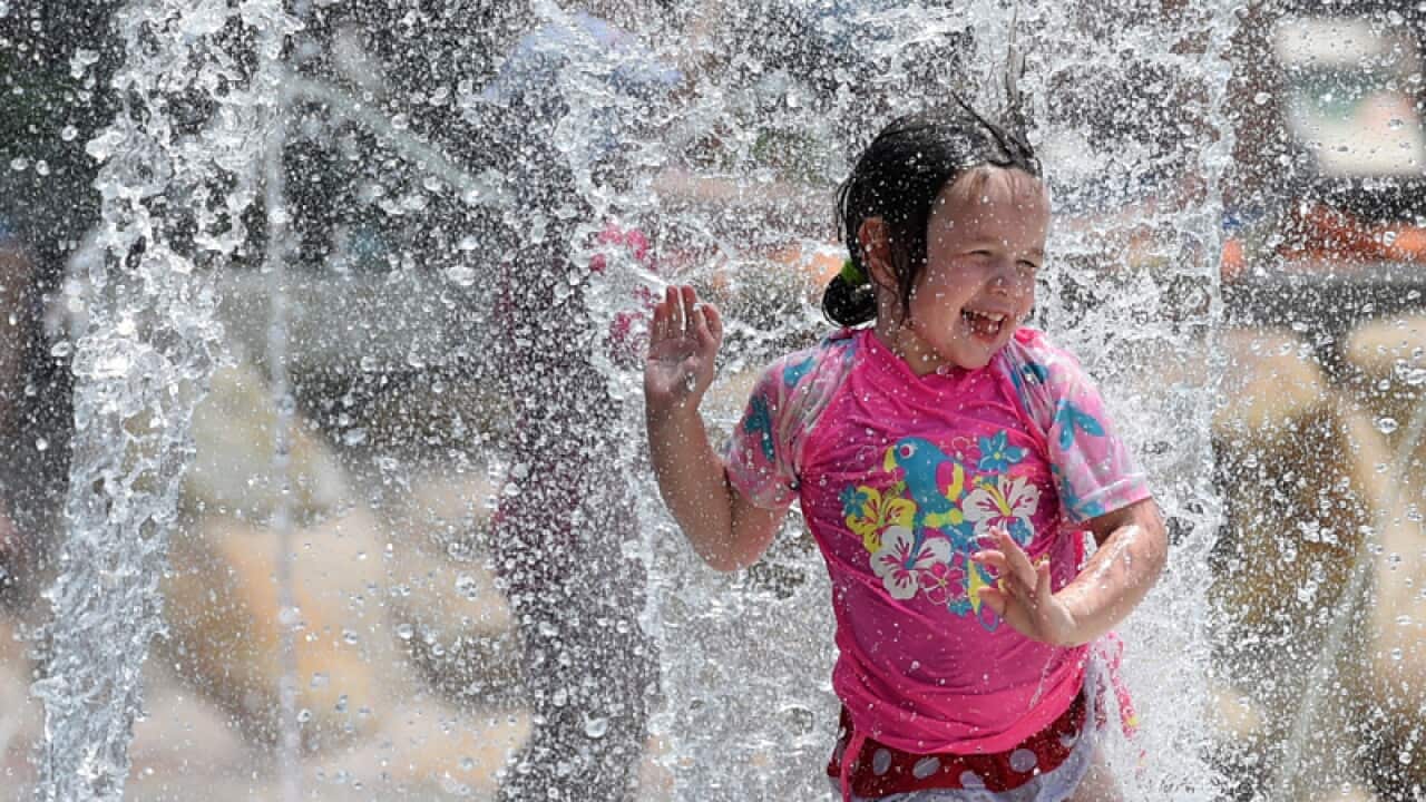 A young girl runs through a fountain