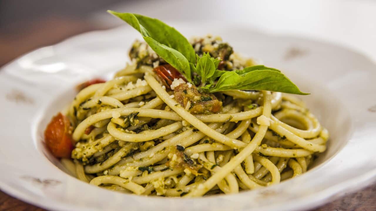 A mound of spaghetti in a rough pesto sits in a shallow bowl.
