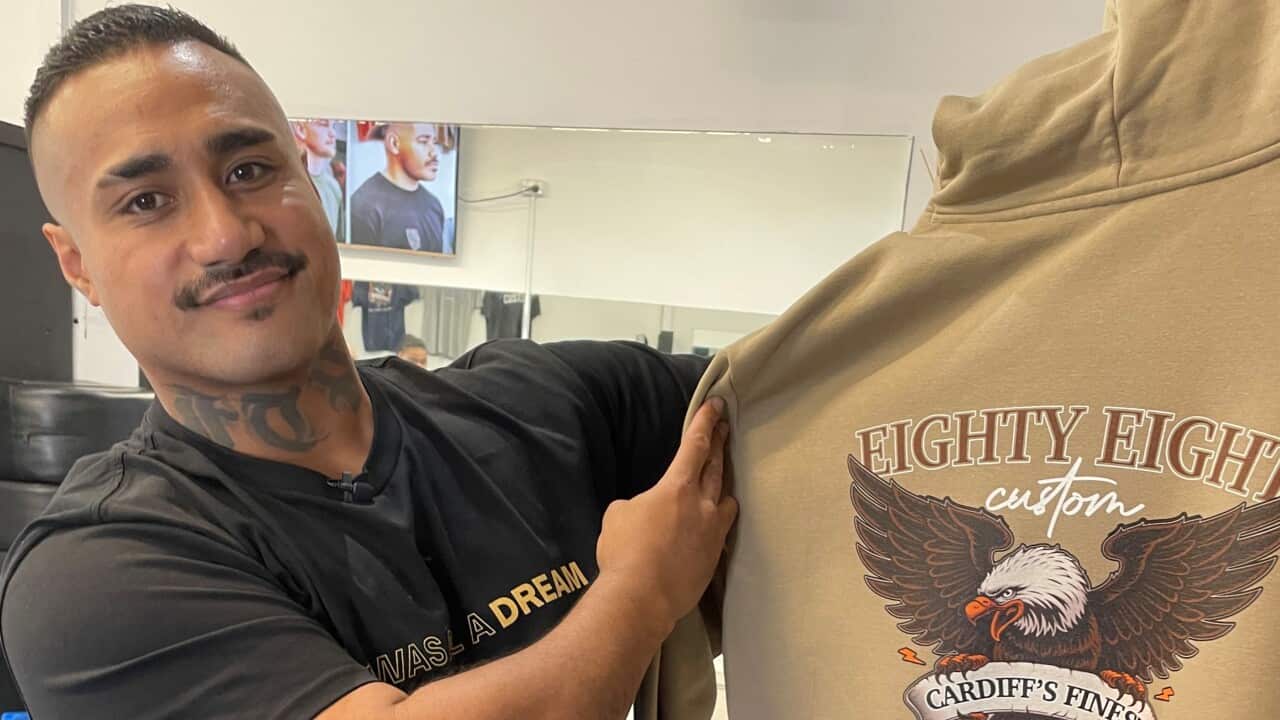 Kinahoi holds up a jumper with his business logo on it.