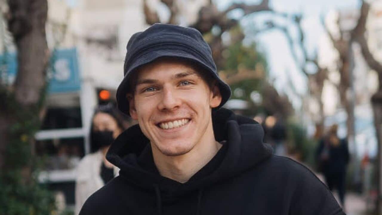 A man walking down a street wearing a black bucket hat and hoodie.