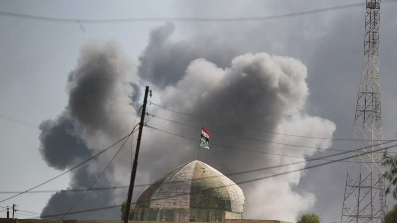 Smoke billows in the background as Iraqi forces, backed by the Hashed Al-Shaabi, raised the Iraqi flag in the town of Tal Afar.
