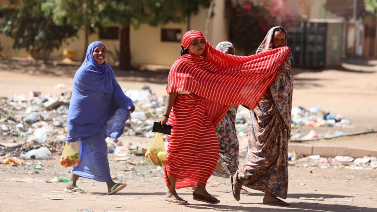 Four women walk on a street in Khartoum.