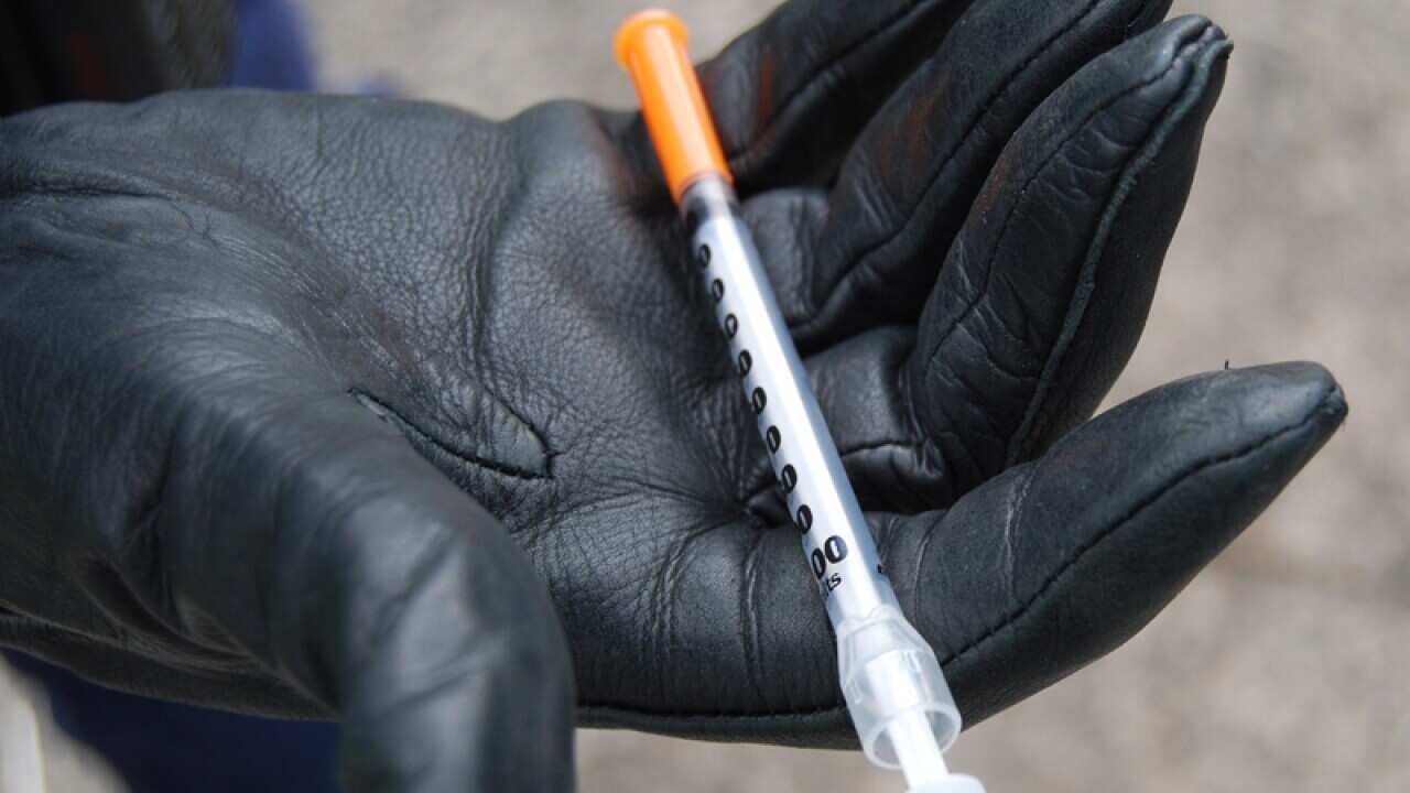 A police officer holds a syringe