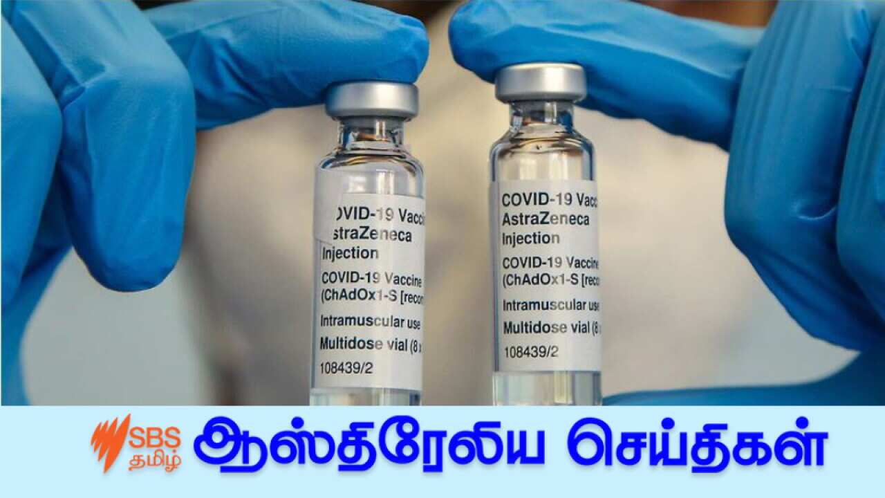A NHS staff member wearing a face mask holds bottles containing Oxford AstraZeneca Covid-19 vaccine.
