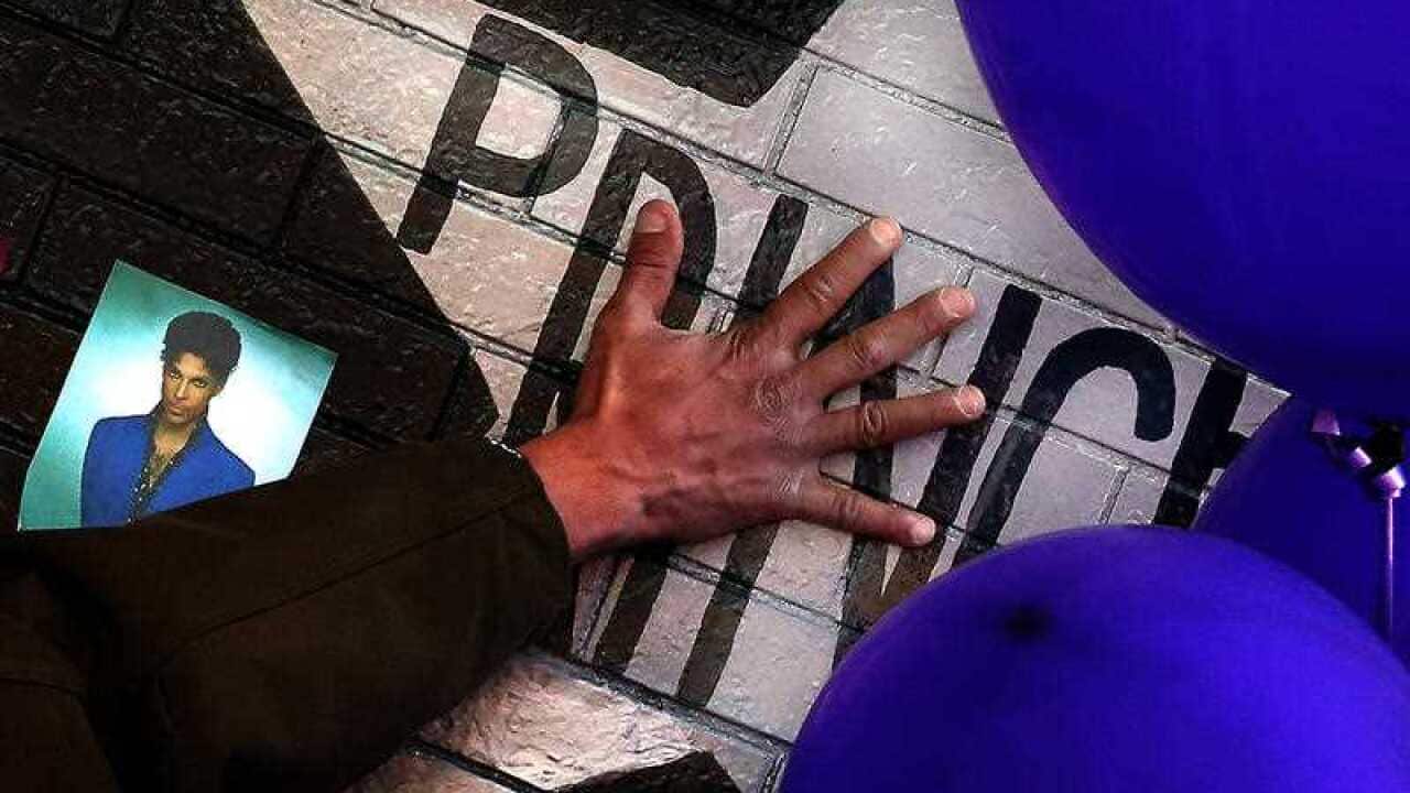 A mourner and fan touches the star for Prince on a wall at First Avenue where the singer often performed
