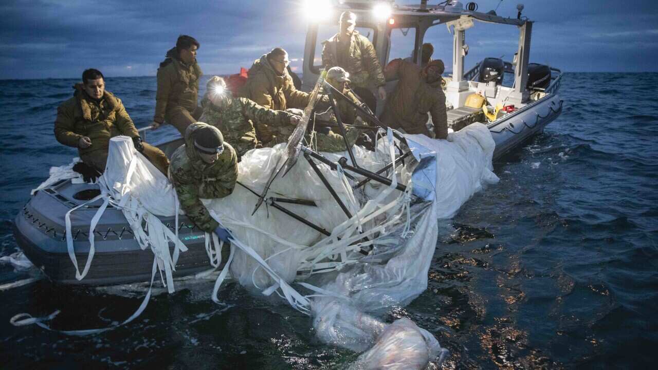 People on a boat retrieving debris that is in the ocean.