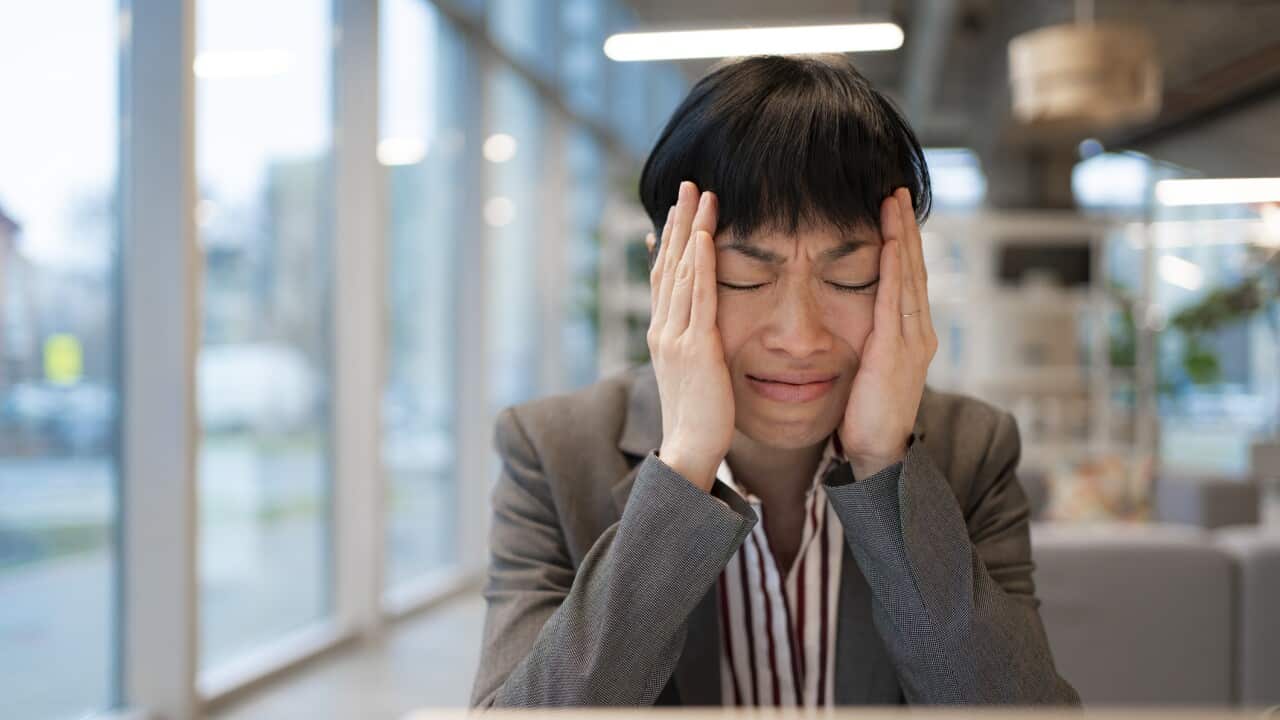 Crying businesswoman suffering burnout and headache at office