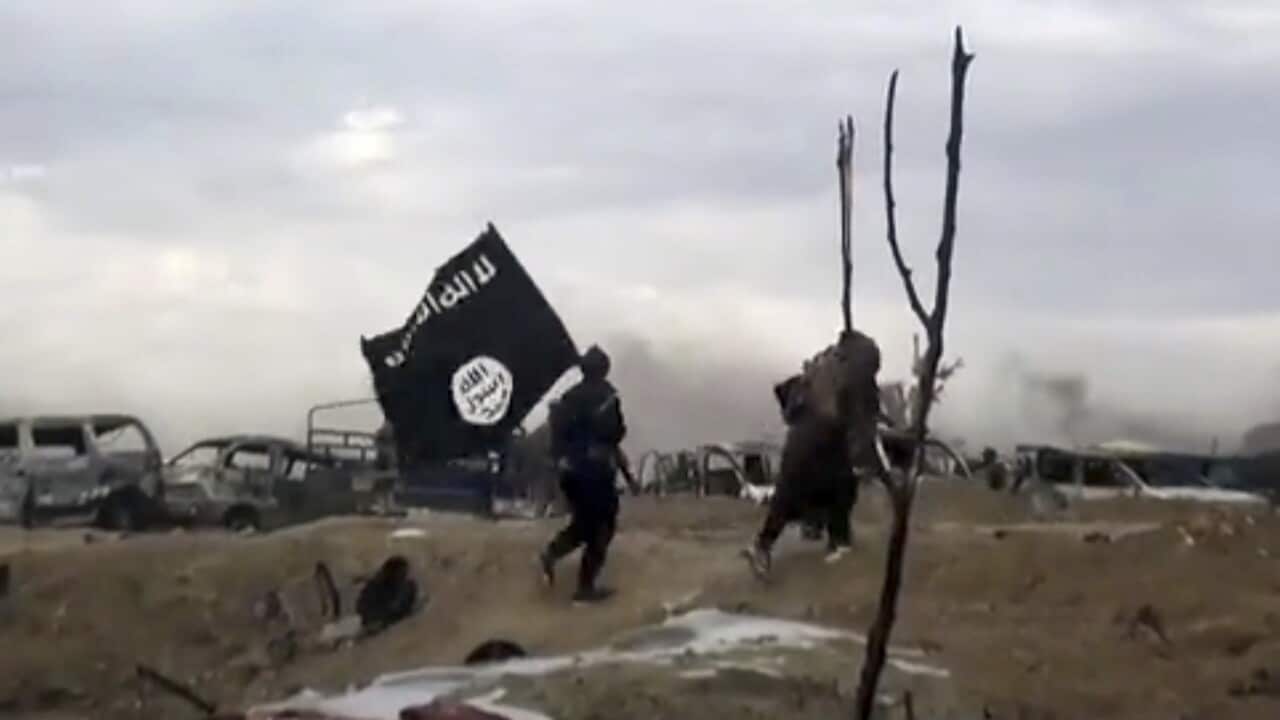 A file photo of IS fighters walking as they hold the group's flag inside Baghouz in Syria, March 2019.