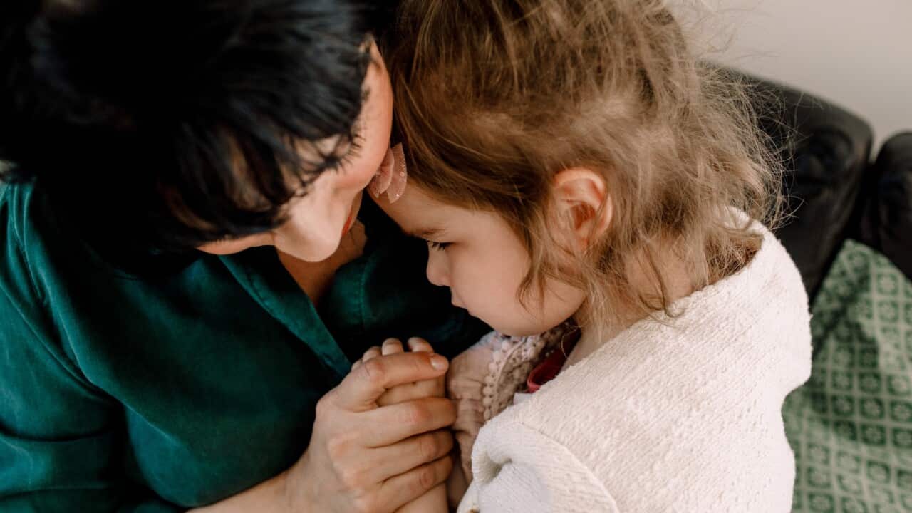 High angle view of mother holding sad daughter while sitting at home