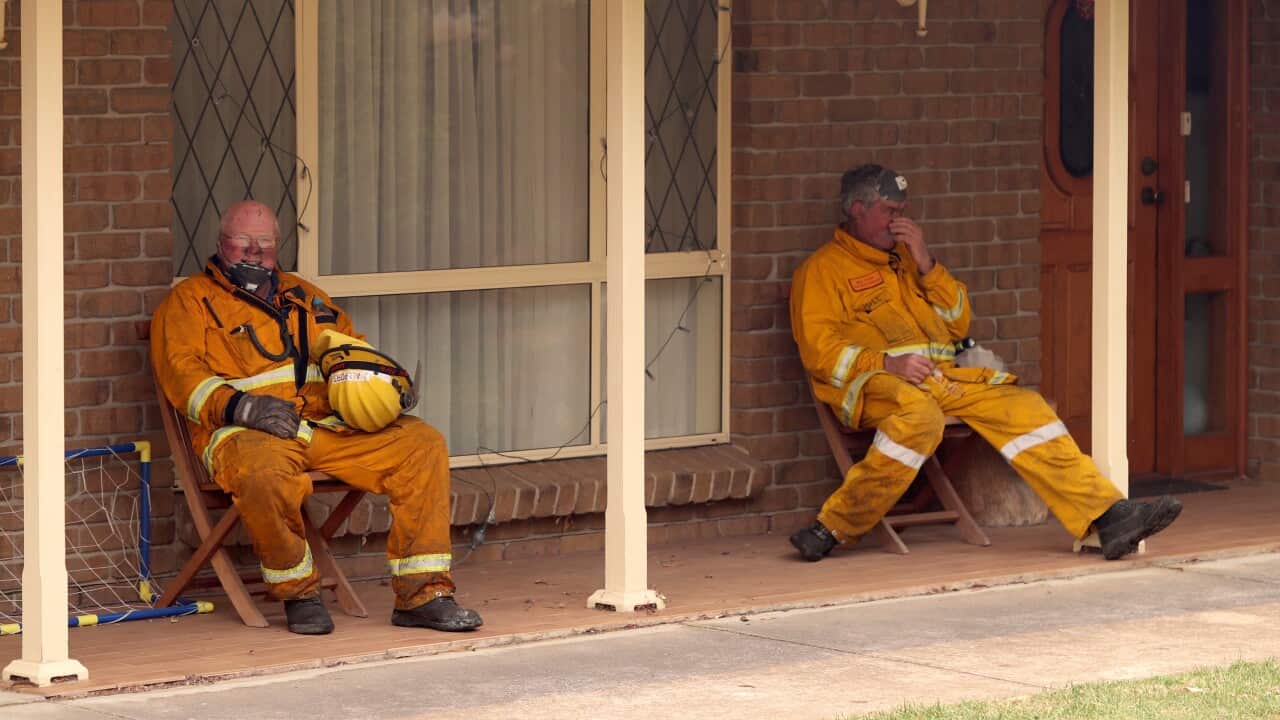 Exhausted Country Fire Service volunteers catch a short break while battling the Adelaide Hills fire on Friday afternoon.